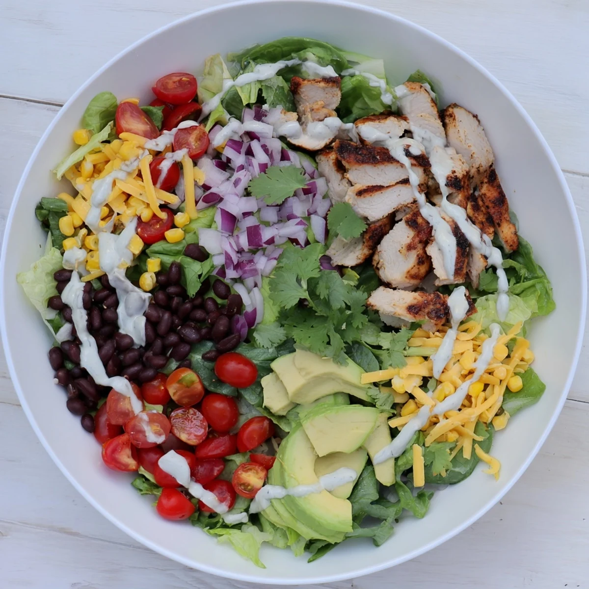 Vibrant bowl of Southwestern chicken salad featuring spiced grilled chicken, black beans, corn, tomatoes, and creamy avocado