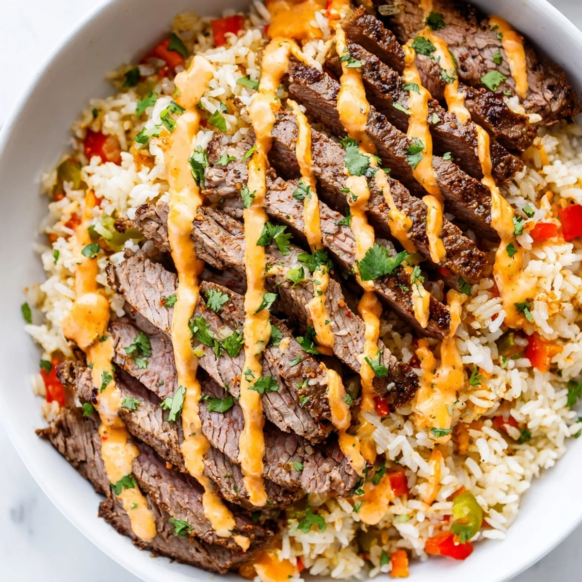 Golden steak queso rice drizzled with warm queso sauce and garnished with chopped cilantro