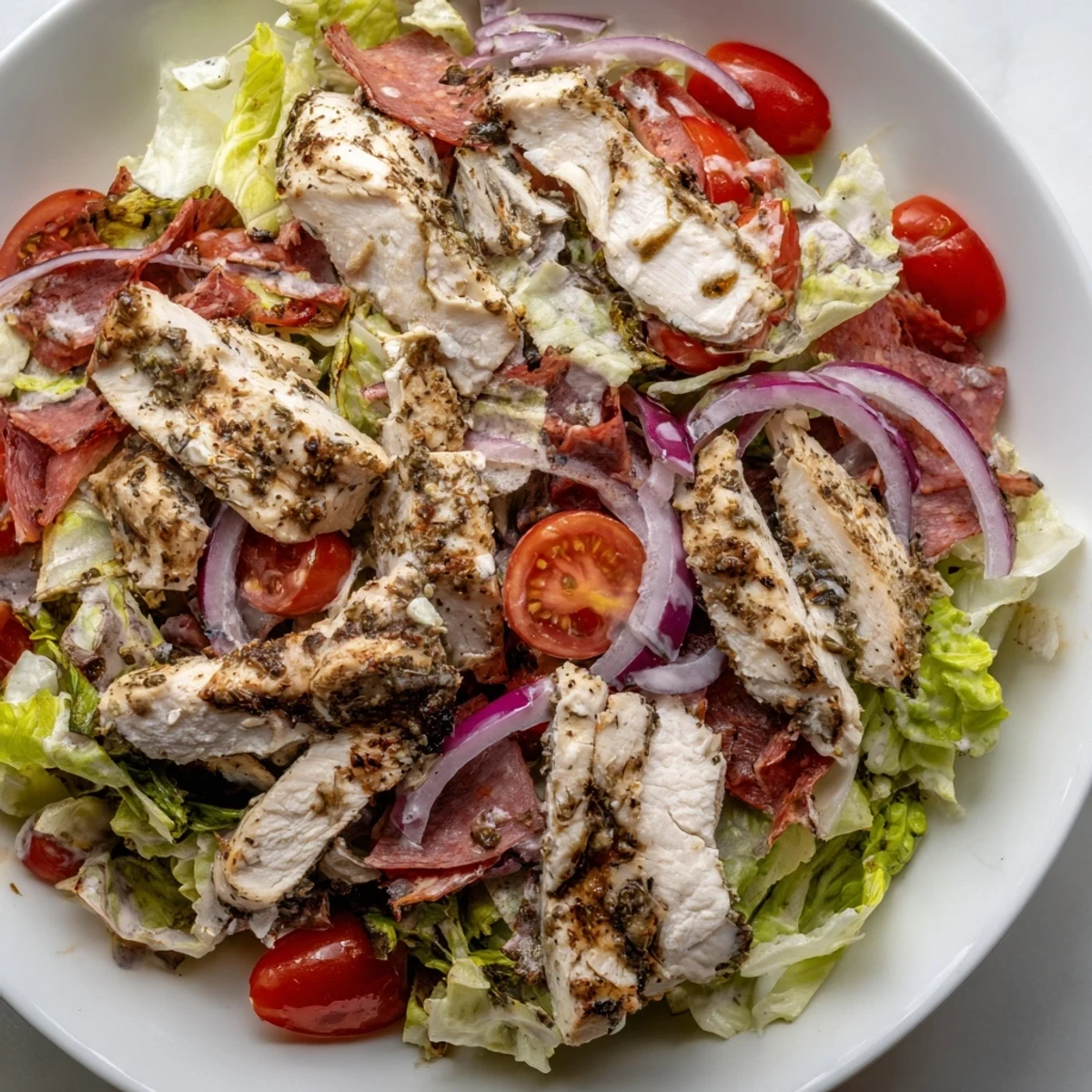 Grilled sliced chicken resting atop Italian Grinder Chicken Salad with provolone and zesty vinaigrette