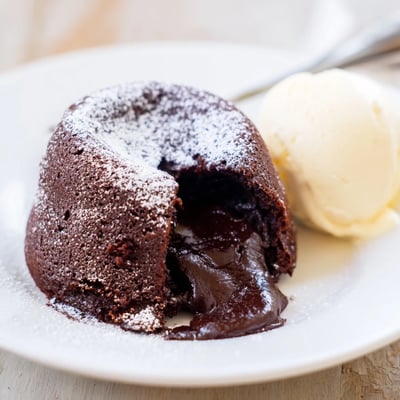 Golden-edged Chocolate Lava Cakes with Vanilla Ice Cream are served hot from the oven, dusted with powdered sugar and berries.