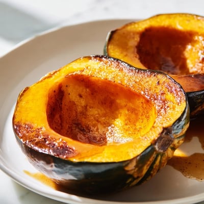 Sliced roasted acorn squash topped with bubbly cinnamon brown sugar butter, a cozy autumn side.