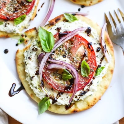 Oven golden Caprese Pita Pizza With Whipped Garlic Feta, melted mozzarella and juicy tomatoes